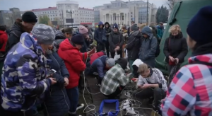 Ucranianos se reúnem em ponto de energia disponibilizado no centro de Kiev, para carregar celulares (Foto: cap. vídeo)